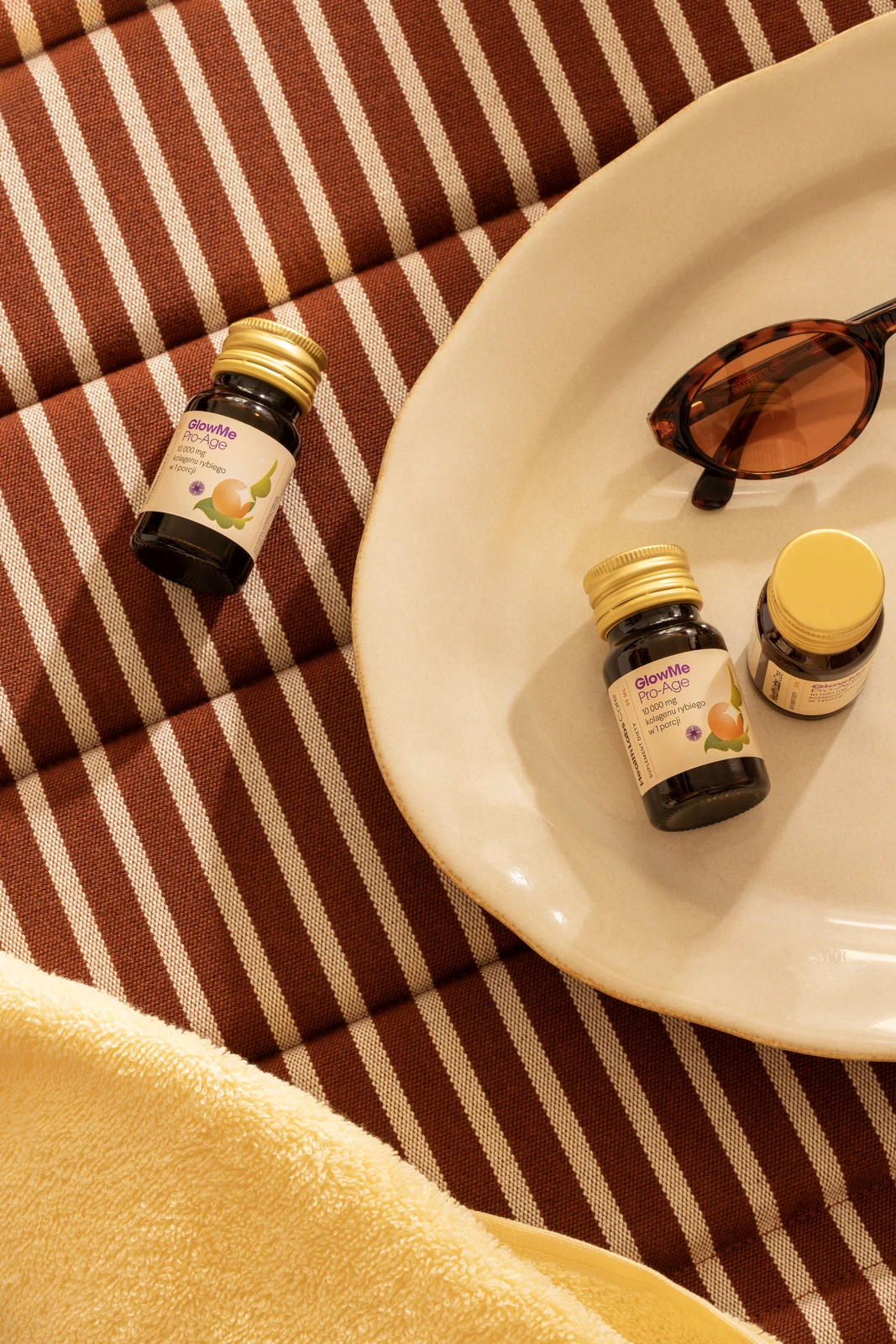 HLC supplements beside sunglasses on a striped sun lounger