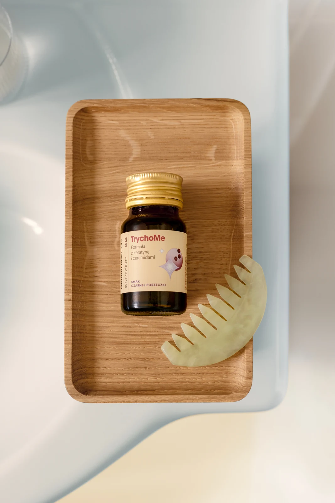 TrychoMe hair care on a wooden tray with a comb